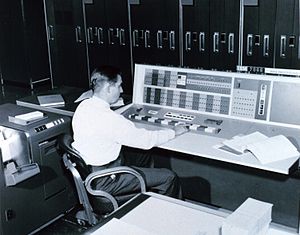 A meteorologist at the console of the IBM 7090...